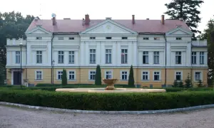 Pałac w Sasinie, z fontanną i zadbanym ogrodem, otoczony drzewami.