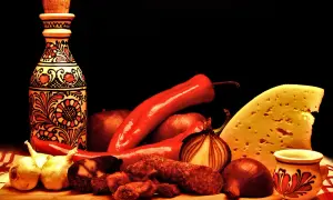 Tradycyjne węgierskie smaki: papryka, kiełbasa, ser i ozdobna butelka.