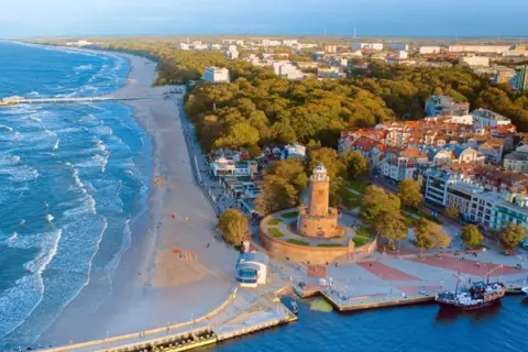 Malownicze miejscowości nad Morzem Bałtyckim: plaża, molo, latarnia morska i urokliwa zabudowa miejska.