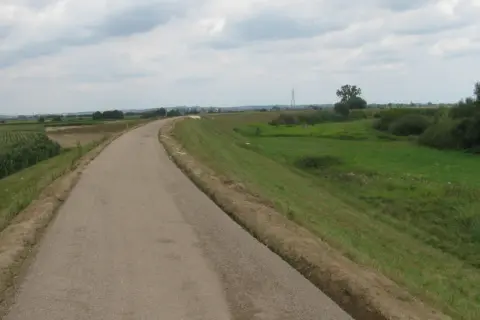 Asfaltowa ścieżka rowerowa velo raba wije się wśród pól kukurydzy i zielonych łąk, zapraszając na przejażdżkę.