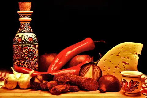 Tradycyjne węgierskie smaki: papryka, kiełbasa, ser i ozdobna butelka.