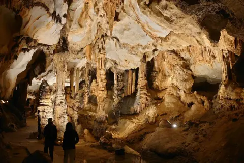 Dwie osoby zwiedzają imponujące jaskinie w Polsce, podziwiając stalaktyty i stalagmity.