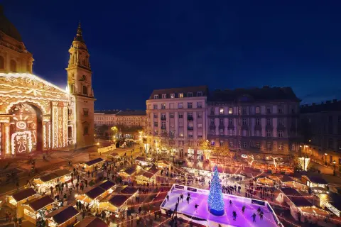 Magiczny budapeszt jarmark bożonarodzeniowy. Tłumy ludzi na lodowisku i przy straganach, oświetlona bazylika w tle.