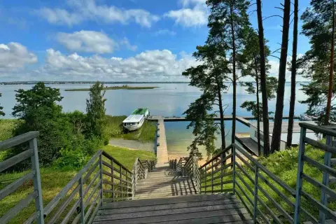 Idealne miejsce na mazury na weekend. Drewniane schody prowadzą do jeziora z łodzią i pomostem.