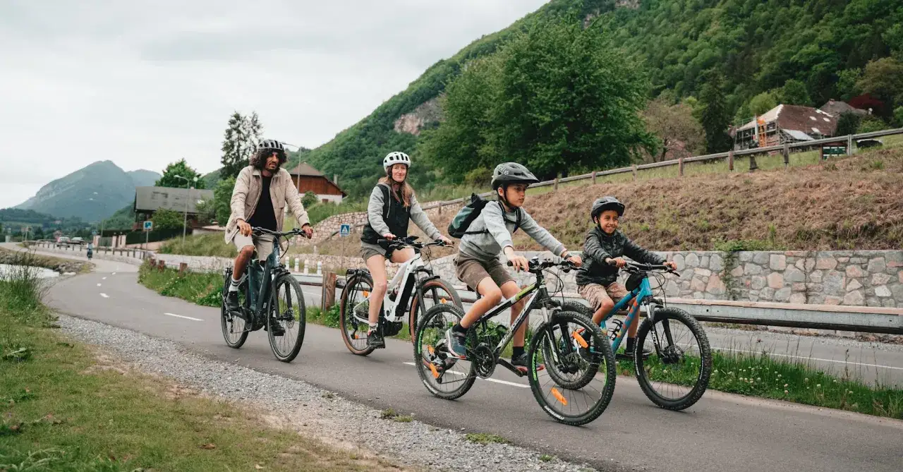 Rodzina na rowerach, pokonująca malowniczą trasę. Dzieci z uśmiechem na twarzach, cieszą się aktywnością. Ile velo dziennie? Tyle, ile radości sprawia!